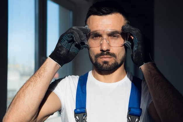 Foto close up, trabalhador da construção civil barbudo usando óculos de proteção