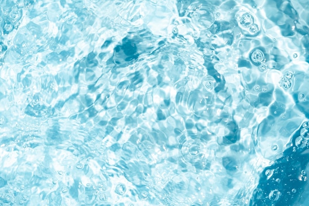 Close-up Transparente azul clara textura da superfície da água com ondulações Abstracto de superfície azul salpicos e bolhas ondas de água refletidas com a luz solar para