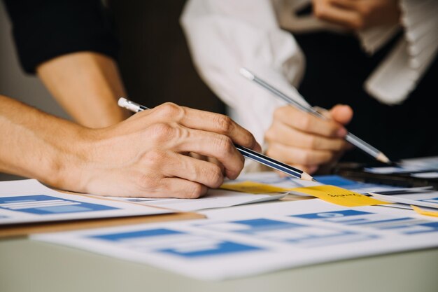 Close up ux desarrollador y ui diseñador lluvia de ideas sobre la interfaz de la aplicación móvil diseño de marco de alambre en la mesa con breif del cliente y código de color en la oficina moderna agencia de desarrollo digital creativa