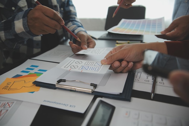 Foto close up ux desarrollador y ui diseñador lluvia de ideas sobre la interfaz de la aplicación móvil diseño de marco de alambre en la mesa con breif del cliente y código de color en la oficina moderna agencia de desarrollo digital creativa