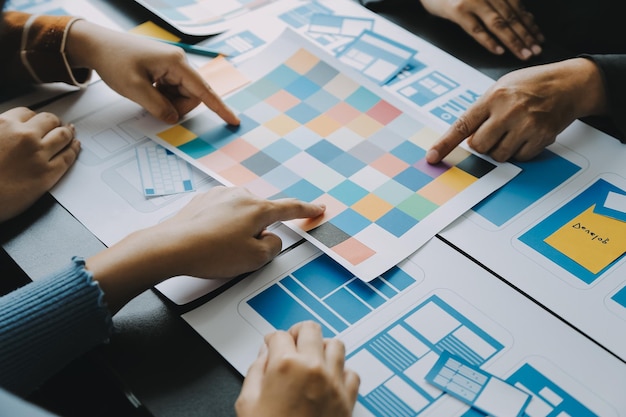 Close up ux desarrollador y ui diseñador lluvia de ideas sobre la interfaz de la aplicación móvil diseño de marco de alambre en la mesa con breif del cliente y código de color en la oficina moderna agencia de desarrollo digital creativa