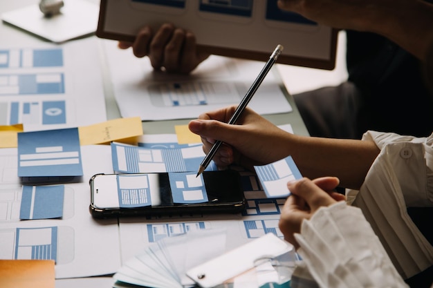 Close up ux desarrollador y ui diseñador utilizan realidad aumentada lluvia de ideas sobre la interfaz de la aplicación móvil diseño de wireframe en el escritorio en la oficina moderna agencia de desarrollo digital creativa