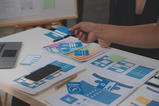 Close up ux desarrollador y ui diseñador utilizan realidad aumentada lluvia de ideas sobre la interfaz de la aplicación móvil diseño de wireframe en el escritorio en la oficina moderna agencia de desarrollo digital creativa