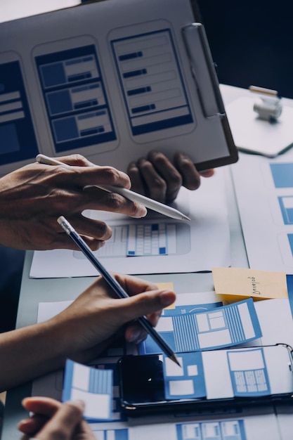 Close-up-UX-Entwickler und UI-Designer brainstormen über Mobile-App-Interface-Wireframe-Design auf dem Tisch mit Kundenbrief und Farbcode in einem modernen Büro Kreative digitale Entwicklungsagentur