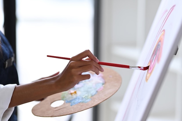 Close-up vista artista mulher segurando paleta e pintando imagens no estúdio de arte