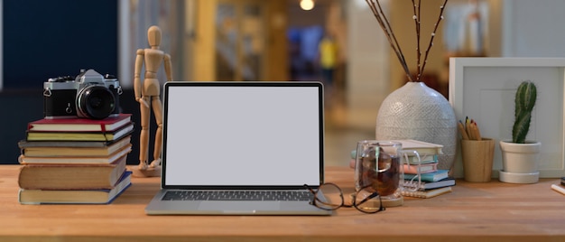 Close-up vista da área de trabalho com simulação de laptop, livros, suprimentos e decorações na mesa de madeira na sala de escritório