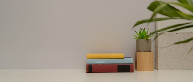 Close-up vista da mesa de estudo simples com cópia espaço, livros, vaso de planta e decorações na mesa branca