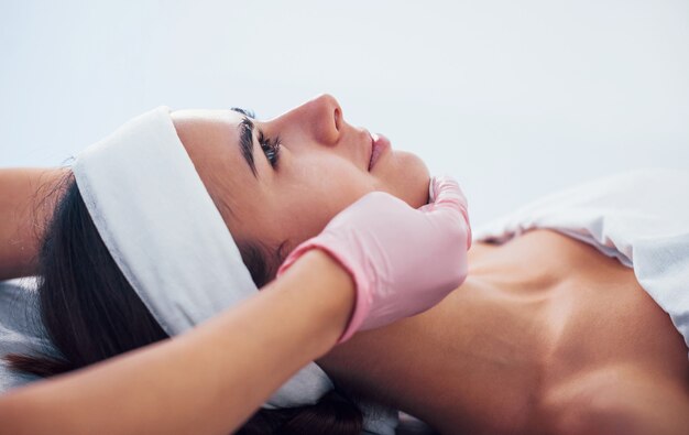 Close-up vista da mulher deitada no salão spa e ter o procedimento de limpeza de rosto por cosmetologista em luvas.