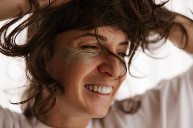 Foto close-up vista da mulher sorridente com manchas de gel verde em casa com os olhos fechados