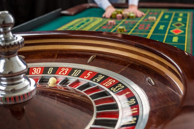 Close-up vista da roleta e pilhas de fichas de jogo em uma mesa verde no casino. Homem entregando fichas de cassino na mesa de roleta