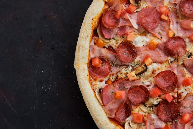 Close-up vista de pizza com presunto, bacon, salsicha, tomate e champignon