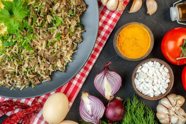 Close-up vista de um delicioso jantar com purê de batata de carne em um prato sobre uma toalha vermelha despojada e especiarias de legumes frescos garrafa de óleo de limão caído em fundo preto