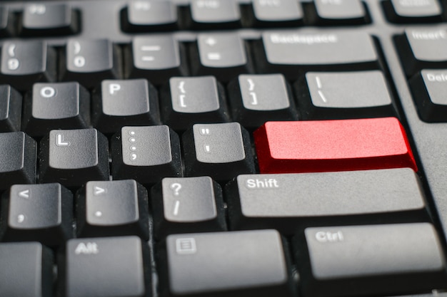 Close-up vista de um teclado de notebook com um botão vermelho na mesa branca do escritório, fundo de tecnologia, espaço vazio para texto