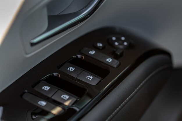 Close-up vista do botão que controla a janela no interior do carro moderno. Detalhe do interior do veículo. Maçaneta da porta com controles de janelas