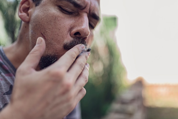 Foto close-up vista do homem fumar cigarro de maconha ao ar livre