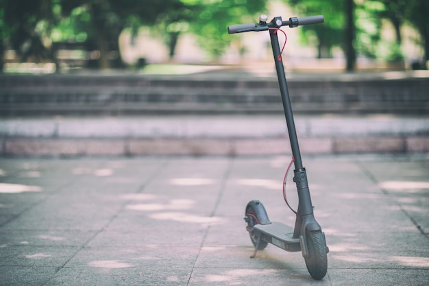 Close-up vista em scooter eletro em ladrilho de rua de cidade em parque ao ar livre