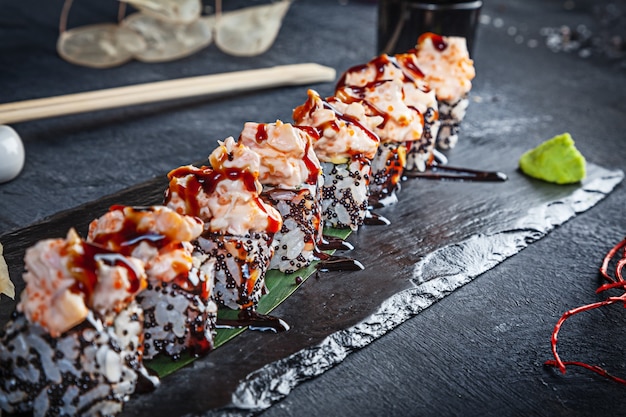 Foto close-up vista no conjunto de rolo de sushi. rolo com enguia e camarão servido na pedra preta sobre fundo escuro. cozinha japonesa. copie o espaço. sushi servido no menu. comida saudável, frutos do mar