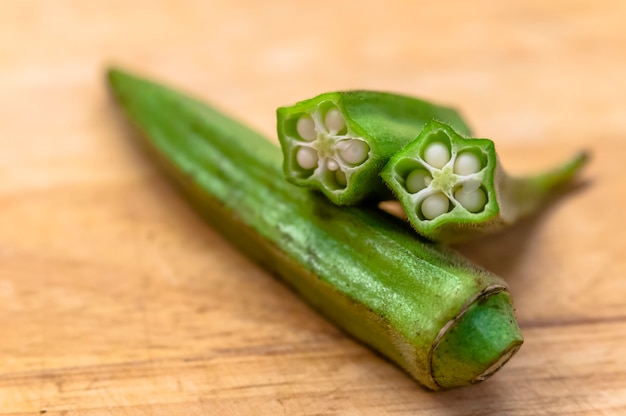 Close-up von Haufen von Bio-Okra auf Holz. Okra Früchte am Schneidebrett