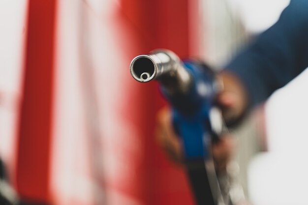 Close uphand segurando o dispenser de combustível da bomba de gasolina Combustível de transporte de conceito de óleo de gasolina