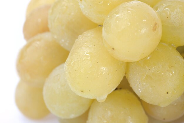 Closeuo parte del racimo de uvas blancas húmedas sobre fondo claro