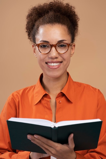 Closeup African American hübsche Frau mit Brille mit einem Notizblock isoliert beige Hintergrund