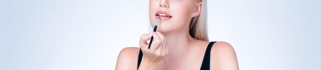 Closeup agradable joven poniendo lápiz labial brillante de moda seductora