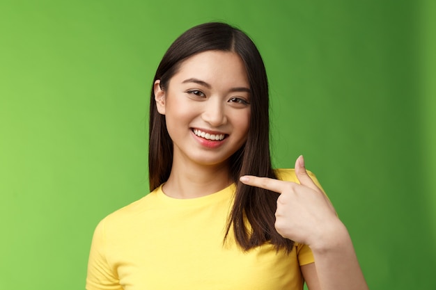 Closeup alegre orgulhosa menina asiática assertiva se apresentar apontando o próprio rosto sorrindo alegremente vangloriar-se ...