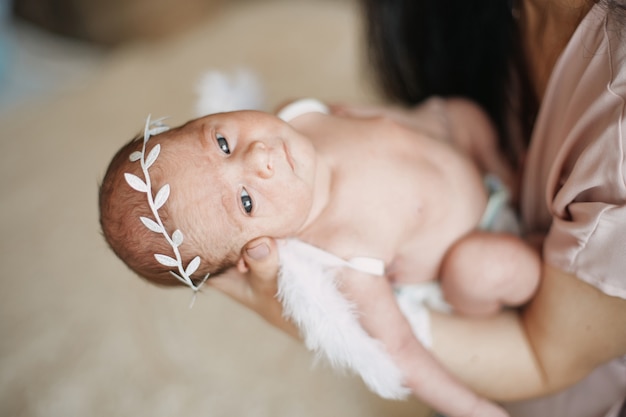 Closeup anjo recém-nascido nas mãos de sua mãe