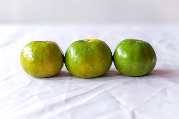 Closeup As laranjas na mesa em pano de fundo branco As laranjas têm casca verde