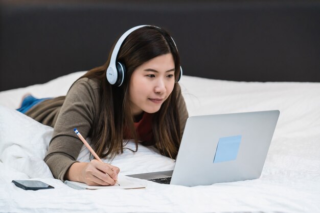 Closeup asiatische Geschäftsfrau Hand schreiben und mit Technologie Laptop für die Arbeit von zu Hause aus