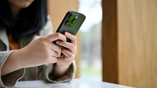 Closeup bastante joven mujer asiática escribiendo en su teléfono charlando con sus amigos