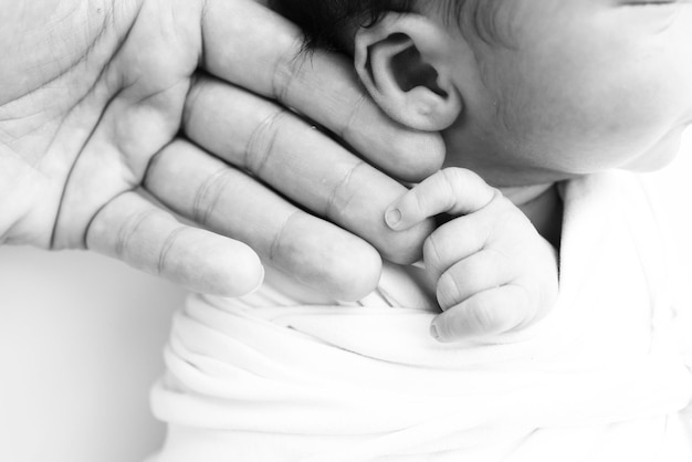 Closeup de bebés mano pequeña cabeza oreja y palma de la madre Macro en blanco y negro Foto de bebé recién nacido después del nacimiento sosteniendo firmemente el dedo de los padres Concepto de familia y hogar Atención médica pediatría