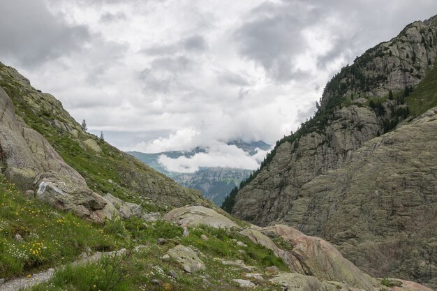 Closeup Berge Szenen, Spaziergang zur Trift Bridge im Nationalpark Schweiz, Europa. Sommerlandschaft, Sonnenscheinwetter, dramatischer bewölkter Himmel und sonniger Tag