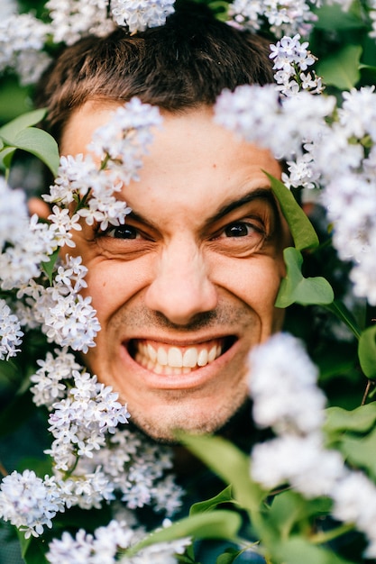 Closeup cara de homem palhaço em arbustos com flores,