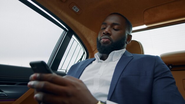 Closeup cara digitando celular no carro Empresário afro conversando com smartphone