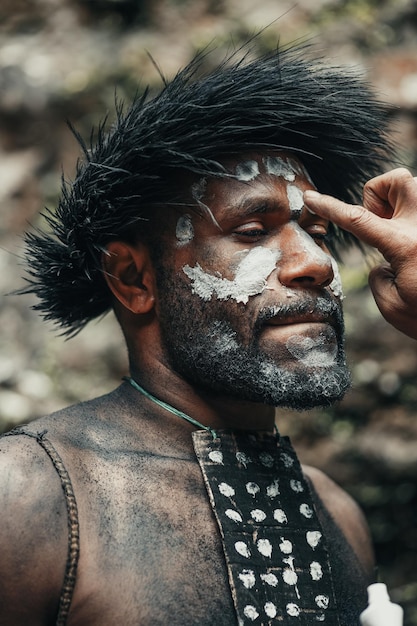 Closeup cara Papua hombre de la tribu Dani pintando su rostro y listo para la guerra o cazar