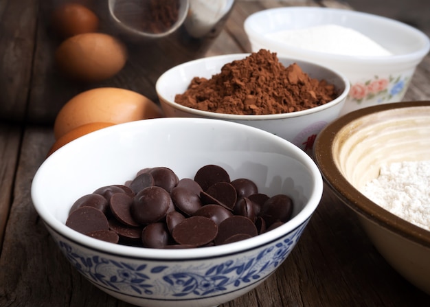 Closeup chocolate escuro em uma tigela pequena. Brownies ingredientes na mesa de madeira.