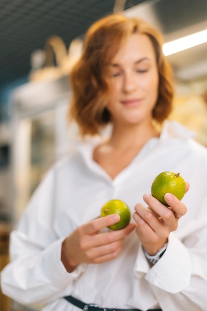 Closeup cortada foto de mulher jovem e atraente segurando nas mãos limão posando em pé na fruta e
