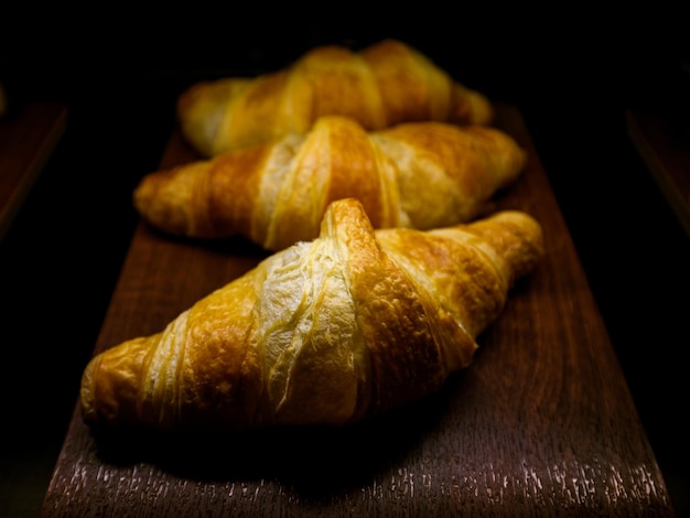 Foto closeup croissant na placa de madeira em fundo escuro