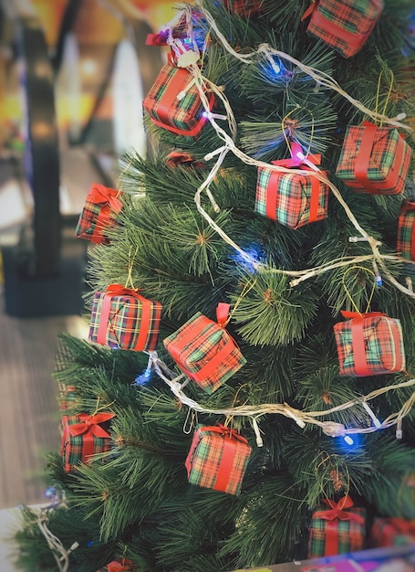 Closeup da árvore de Natal decorada com bolas vermelhas brilhantes no fundo borrado cintilante.