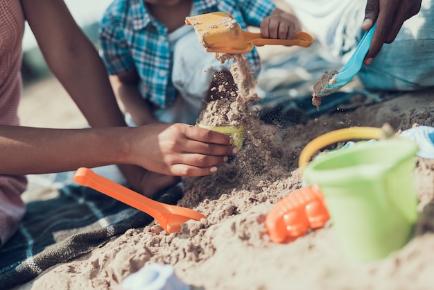 Closeup da família é brincar com brinquedos na praia de areia do rio