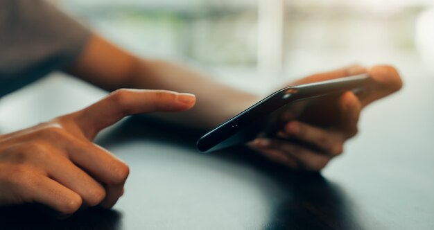 Closeup da mão da jovem mulher segurando o smartphone e conversando com os amigos na rede social.