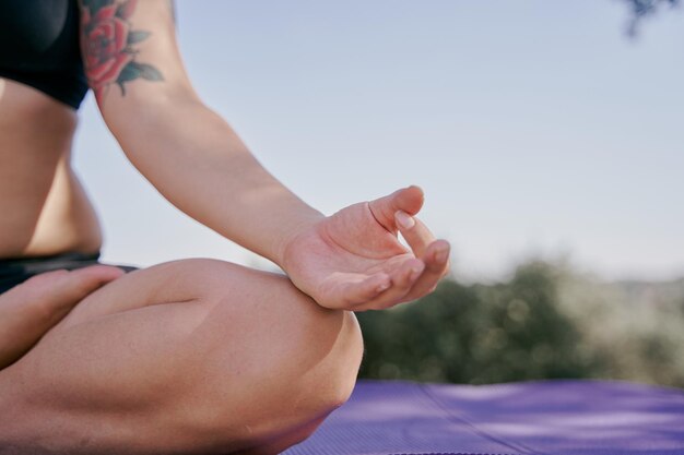 Closeup da mão de mulher tatuada em postura de ioga meditando