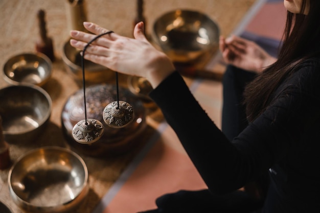 Closeup da mão de uma mulher segurando sinos tibetanos para terapia de som pratos tibetanos