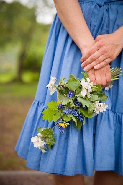 Closeup da mão de uma mulher segurando um galho de macieira florescendo Blues se veste como pano de fundo