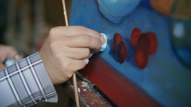 Closeup da mão do artista manchando tintas a óleo na tela na oficina de arte