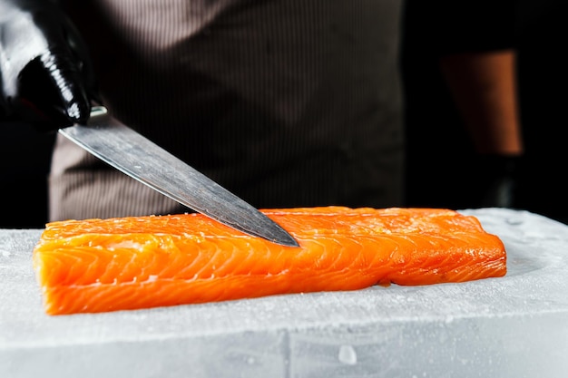 Closeup da mão do chef preparado para cozinhar fundo preto de filé de salmão fresco