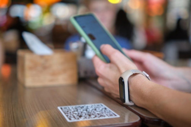 Closeup da mão do convidado pedindo refeição no restaurante enquanto digitaliza o código qr com o celular para o menu online