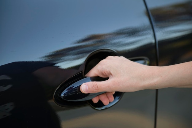 Closeup da mão do motorista abrindo a porta da frente do carro