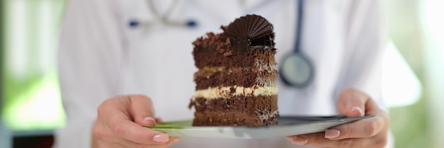 Closeup da mulher nutricionista segurando nas mãos um pedaço de bolo de chocolate dieta alimentar saudável